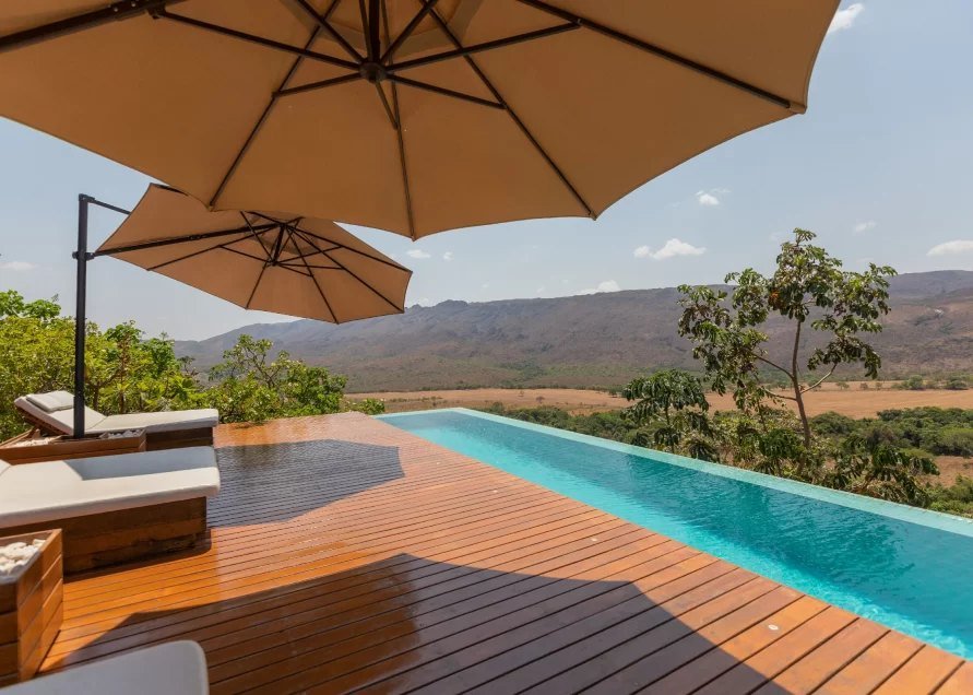 Ombrelones sobre o deck da piscina de borda infinita, com a Serra da Canastra ao fundo